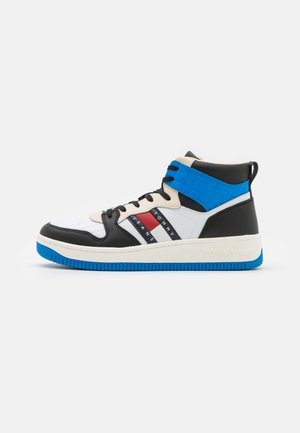 Zapatilla de caña alta con una combinación de colores negra, blanca y azul. Presenta una parte superior de cuero y textil suave, cordones en contraste y acentos de marca.