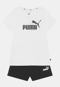 Camiseta blanca con logo negro de "PUMA" y gráfico de puma saltando, combinada con pantalones cortos negros que presentan el logo de "PUMA" en el dobladillo. Manga corta, corte relajado.