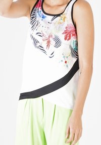 Top bianco smanicato con stampa floreale e animale colorata, rifinitura nera lungo il colletto e un accento nero diagonale lungo il fondo.