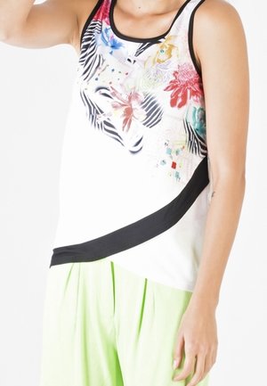 Witte tanktop met kleurrijke bloemen- en dierenprint, zwarte rand langs de halslijn en een diagonale zwarte accent aan de onderkant.