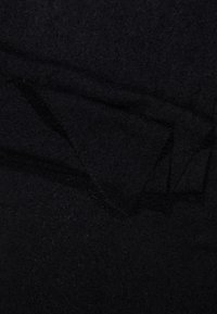 Sort tekstilstof med en blød, struktureret overflade, der har folder og en subtil glans, hvilket indikerer et let og hyggeligt materiale.