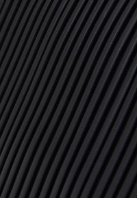 Svart ribbat tyg med en strukturerad yta, som har jämnt fördelade vertikala åsar, vilket skapar ett mönstrat utseende.