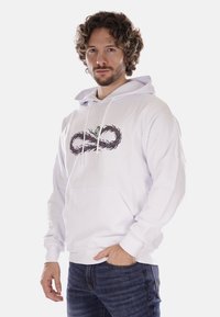 Felpa bianca con cappuccio caratterizzata da un design grafico di un simbolo dell'infinito con intricati motivi a vite e un accento verde. Tasca a marsupio sul davanti.