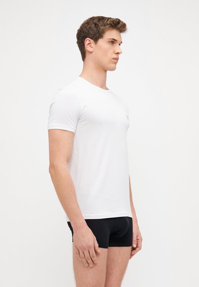 White cotton t-shirt with short sleeves, round neckline, fitted shape. Features small printed logo on the chest, smooth texture.