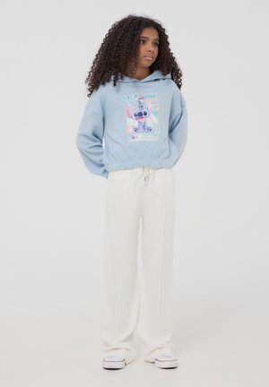 Felpa azzurra con design grafico, orlo elastico, abbinata a pantaloni bianchi a gamba larga con una texture morbida.