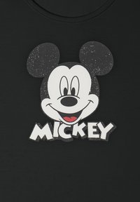 Volto sorridente di Topolino con orecchie grandi e il nome "MICKEY" in lettere bianche in grassetto su uno sfondo di tessuto nero.