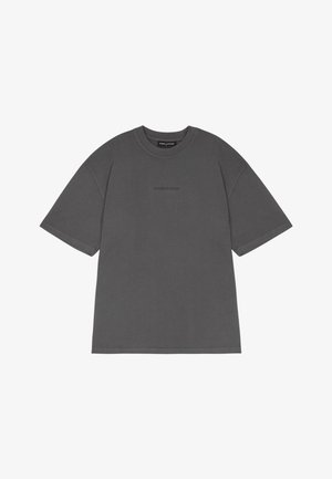 Szürke pamut póló rövid ujjakkal, kerek nyakkivágással és középen bélyegzett logóval. Lazább szabású és sima tapintású.