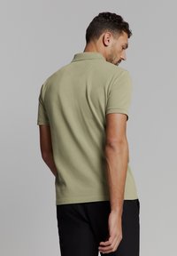 Korte mouwen polo in olijfgroene kleur, gemaakt van zacht katoen, met een klassieke kraag en een rechte zoom met minimale afwerking.