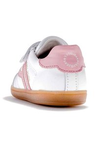 Zapatilla blanca con acentos rosas, que cuenta con una correa de velcro, forma redondeada, suela de goma, textura suave y detalle del logo en el talón.