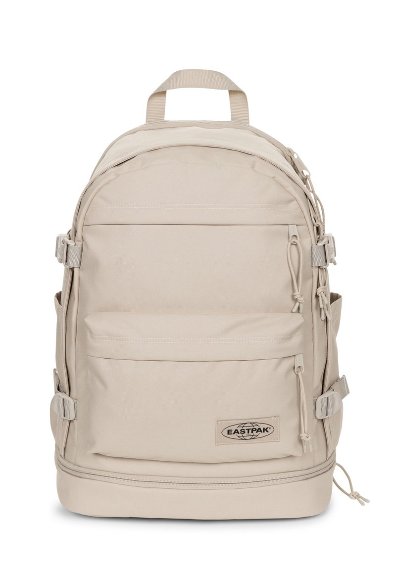 Zaino Eastpak beige dalla forma arrotondata, con spallacci regolabili, numerose tasche e una patella con il marchio. Realizzato in tessuto resistente con una superficie liscia.