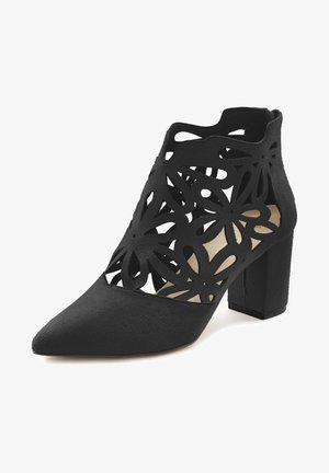 Black ankle boot with a pointed toe and block heel, featuring intricate floral cut-outs on synthetic material, textured surface, and a neutral interior.