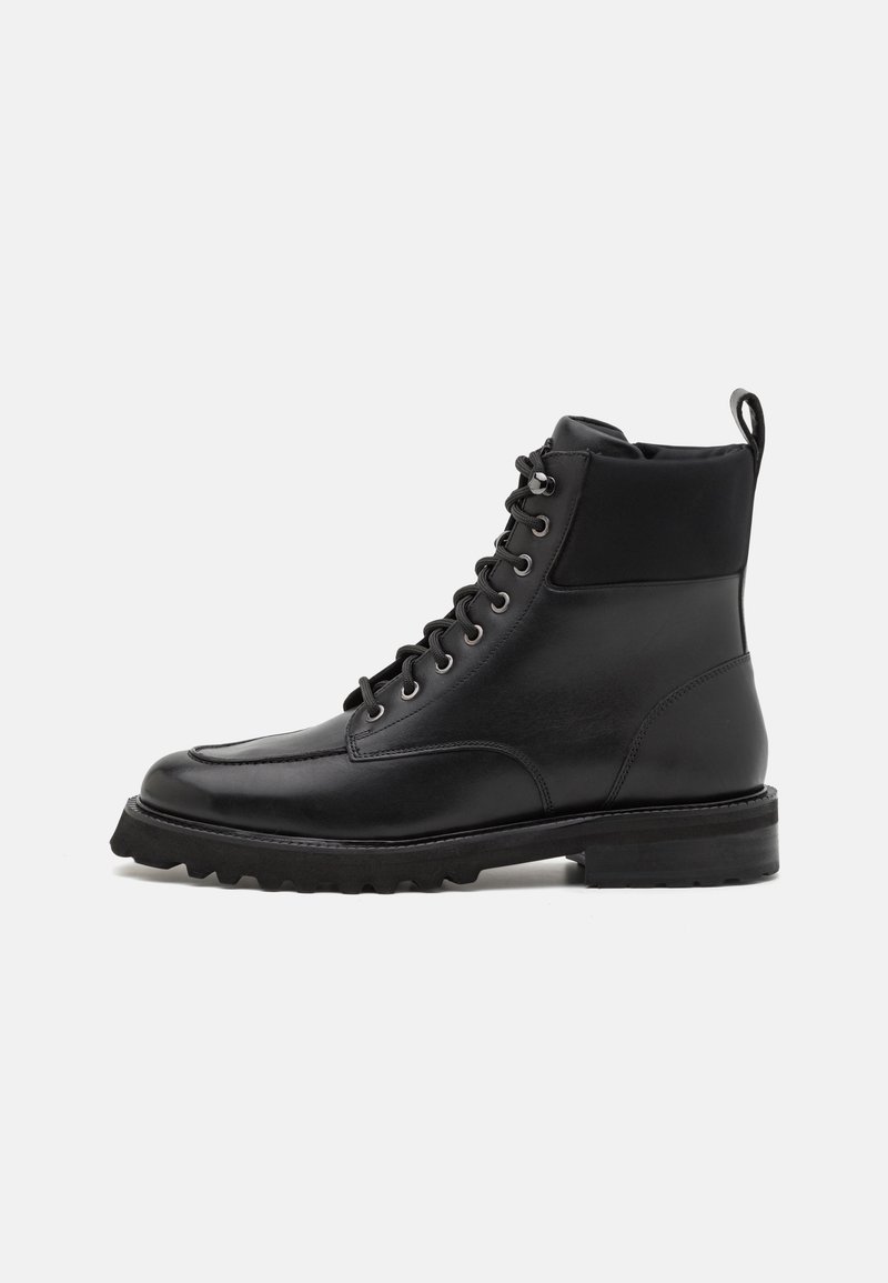 Bottine noire en cuir à lacets avec semelle robuste, col rembourré et languette à l'arrière, conçue pour la durabilité et le style.