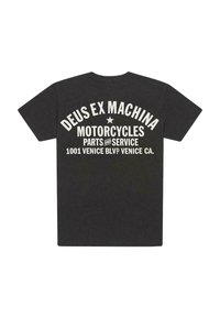 Camiseta de algodón negra de manga corta. La parte posterior presenta un texto gráfico en blanco que dice "DEUS EX MACHINA MOTORCYCLES PARTS AND SERVICE" y detalles de ubicación.