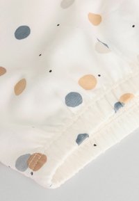 Tissu blanc avec des pois multicolores en bleu, beige et noir. Bord élastiqué au bas, texture lisse et design léger.