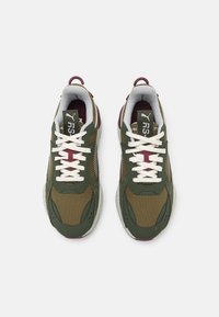 Paire de baskets Puma RS-X vertes et marron avec des lacets blancs vue de dessus sur un fond blanc uni.