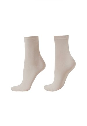 Paar beige, knöchellange, transparente Socken auf Fußpuppen vor weißem Hintergrund gezeigt.