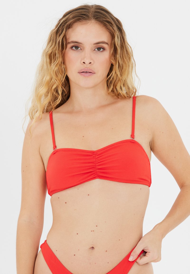 Top bikini rosso con spalline regolabili e texture raccolta al centro, caratterizzato da un design bandeau e una finitura liscia.