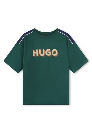 T-shirt vert foncé à manches courtes avec des rayures navy aux épaules et un texte "HUGO" en style 3D rétro en beige et orange sur le devant.