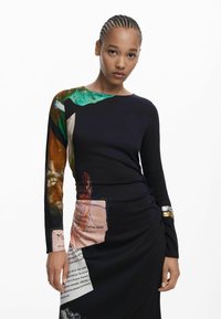 Robe noire à manches longues ornée d'imprimés abstraits colorés et de détails textuels. Tissu doux, design ajusté, avec une texture froncée à la taille.