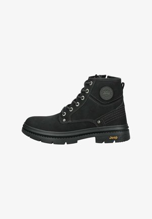 Czarne botki za kostkę wykonane z materiału syntetycznego o teksturowanym wykończeniu, z metalowymi oczkami w kolorze srebrnym, naszywką z logo oraz grubą gumową podeszwą.