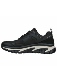 Schwarz sportlicher Schuh mit strukturiertem Obermaterial, Schnürung vorne und gepolsteter Sohle, die einen weißen Akzent entlang der Zwischensohle und ein starkes Profilmuster aufweist.