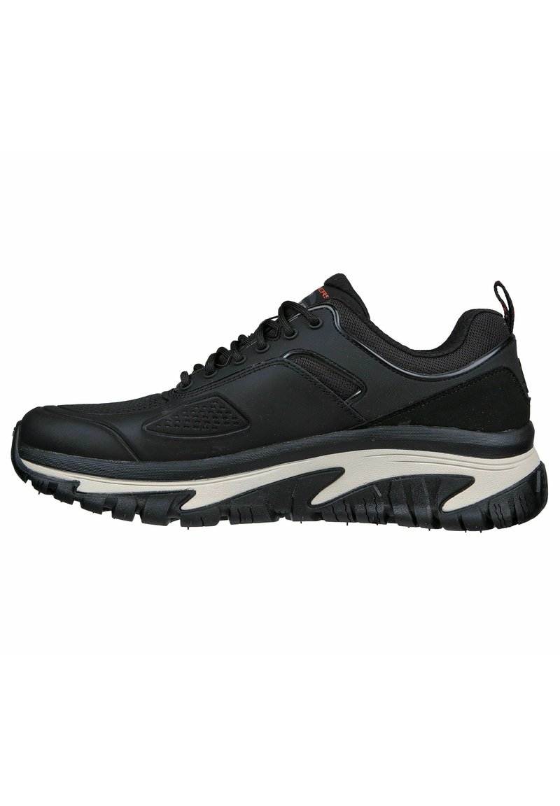 Schwarz sportlicher Schuh mit strukturiertem Obermaterial, Schnürung vorne und gepolsteter Sohle, die einen weißen Akzent entlang der Zwischensohle und ein starkes Profilmuster aufweist.