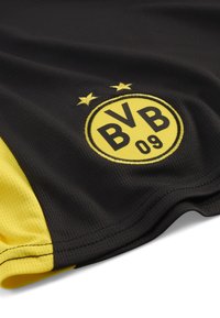 Maglia sportiva nera con accenti gialli, caratterizzata da un logo circolare con "BVB 09" e due stelle sopra. Realizzata in tessuto mesh traspirante.