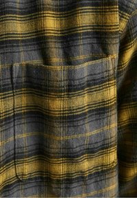 Tessuto a quadri giallo e nero con una finitura morbida e testurizzata; presenta strisce orizzontali e verticali prominenti.