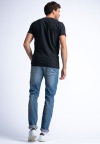 Černé bavlněné tričko, slim fit, v kombinaci se světle modrými džíny, ohrnutými rukávy a bílými teniskami. Jednoduchý design bez viditelných vzorů.