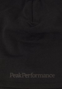Beanie nera con una texture liscia e morbida e un logo discreto, che mostra un design aderente adatto per l'uso all'aperto.