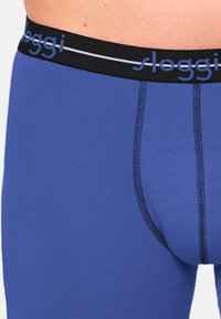 Blaue Baumwollboxershorts mit schwarzem elastischem Bund, der das "sloggi"-Logo in Hellblau trägt. Glatte Textur, körpernahe Passform mit kontrastierenden Nähten.