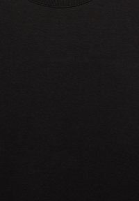 Gros plan sur un tissu noir montrant la texture tricotée et l'encolure ronde côtelée d'un vêtement.