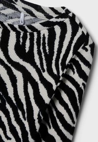 Crno-bijela rebrasta pulover s uzorkom zebra pruga, s širokim dekolteom i teksturiranim materijalom.