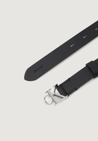 Black leather belt with a textured finish, featuring a silver CK logo buckle. Includes adjustment holes along the strap.