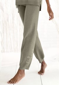 Oliivroheline kudumisest valmistatud joggerite püksid kitsenevate pahkluude mansettidega ja trükitud logoga. Pehme tekstuur, mugav lõige ning külgmine lõhe vööl.