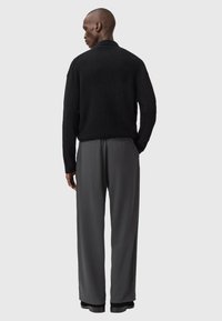 Black textured knit sweater paired with gray wide-leg trousers, featuring a smooth fabric and subtle side pocket detailing.