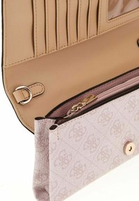 Portefeuille en tissu rose pâle à surface texturée, doté d'un compartiment zippé, de fentes pour cartes et d’une fermeture à pression. L'intérieur est en cuir beige.