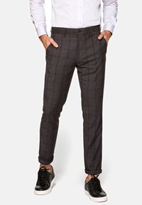 Szare spodnie w kratę o wąskim kroju, z bocznymi kieszeniami i gładką fakturą, zestawione z czarnymi sneakersami.