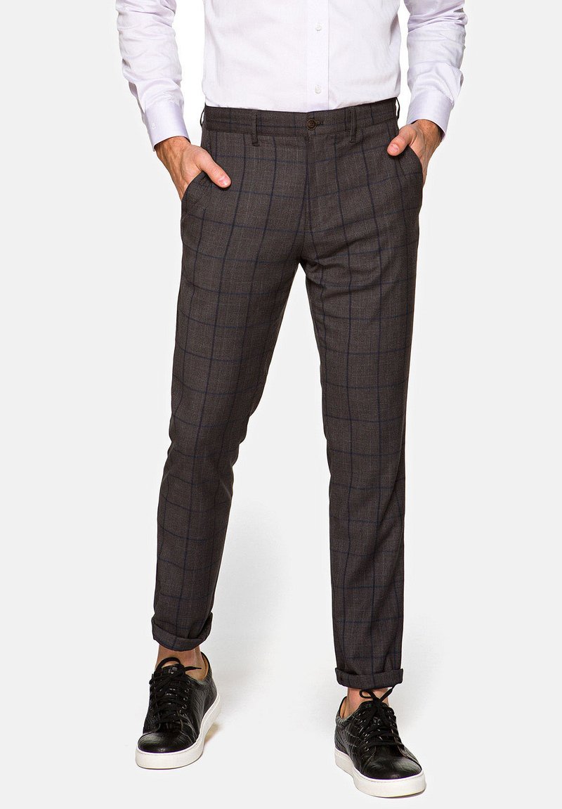 Szare spodnie w kratę o wąskim kroju, z bocznymi kieszeniami i gładką fakturą, zestawione z czarnymi sneakersami.
