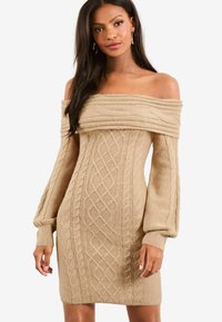 Pletené off-the-shoulder šaty v béžové barvě, s kabelovými vzory, dlouhými nafouklými rukávy a obtaženou siluetou. Měkká textura a elastický materiál.