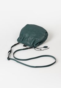 Türkise Lederhandtasche mit einem weichen, gerafften Design, Reißverschluss, verstellbarem Schulterriemen und einer Kettenakzentuierung. Glatte Textur mit matter Oberfläche.