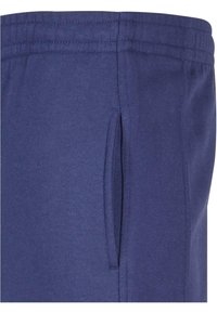 Marineblaues Sweatpants aus weichem Material, mit seitlicher Tasche und elastischem Bund mit mehreren Nahtlinien für Struktur.