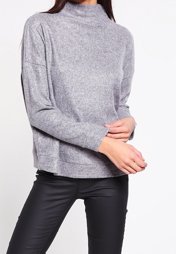 Top grigio, texturizzato, a maniche lunghe con colletto alto. Abbinato a pantaloni neri aderenti. Design semplice con vestibilità rilassata.
