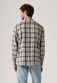 Rutete skjorte i beige og svart, med lange ermer, krage og knappede mansjetter. Mykt stoff med en avslappet passform.