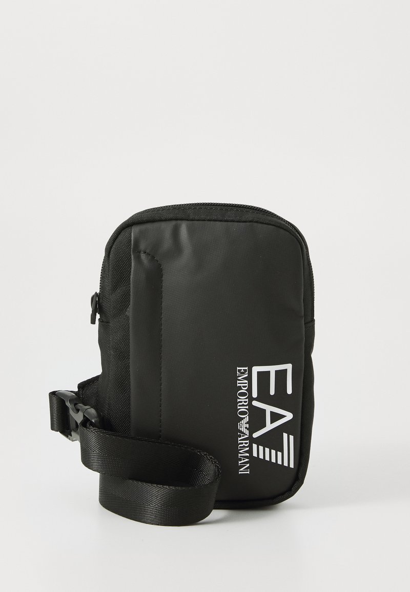 Petit sac bandoulière noir avec fermeture éclair et une sangle ajustable. Logo audacieux "EA7 EMPORIO ARMANI" affiché sur le devant.