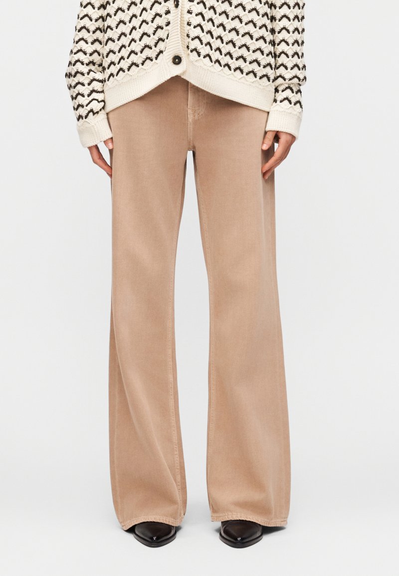 Μπεζ παντελόνια φαρδιάς γραμμής συνδυασμένα με  μαύρα μυτερά παπούτσια και εκρού ζακέτα με μαύρα ζιγκ ζαγκ μοτίβα.