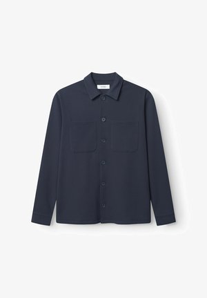 Jūras zilas krāsas garām piedurknēm krekls ar pogām priekšpusē, divām krūšu kabatām un teksturētu audumu. Iezīmēts ar norādītu apkakli un pogājamām aprocēm.