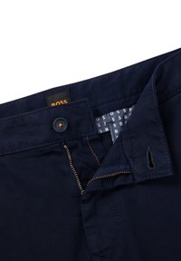 Námorně modré kalhoty se zipem, knoflíkovým zapínáním a oranžovým prošíváním. Uvnitř pásu se nachází textilní štítek s logem "BOSS".