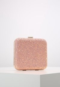 Pochette rose pailletée de forme carrée, texture lisse, fermoir métallique et finition brillante qui reflète la lumière.