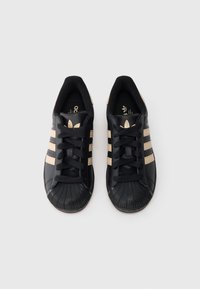 Μαύρα δερμάτινα αθλητικά παπούτσια με τρεις μπεζ ρίγες, μαύρα κορδόνια και υφασμένο λαστιχένιο κάλυμμα στα δάχτυλα. Λογότυπο και εμπορικό σήμα στη σόλα εσωτερικά.